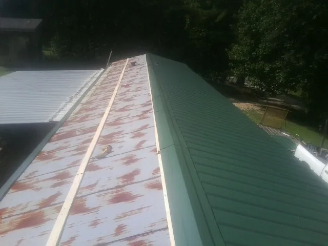 Old rusted panels beside newly installed green metal roofing — Wind Damage Roof Repair by Roofing Brothers in Annville