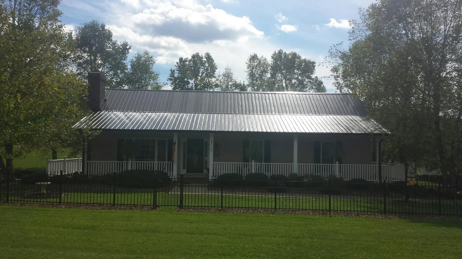 Gray metal roof on a brick ranch with a full width front porch — Gutter Guard Installation work by our crew in Annville