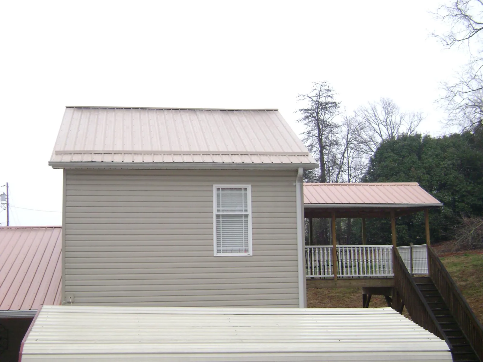 Tan metal roofs on a two story addition and attached porch, from a Roof Replacement job in Annville