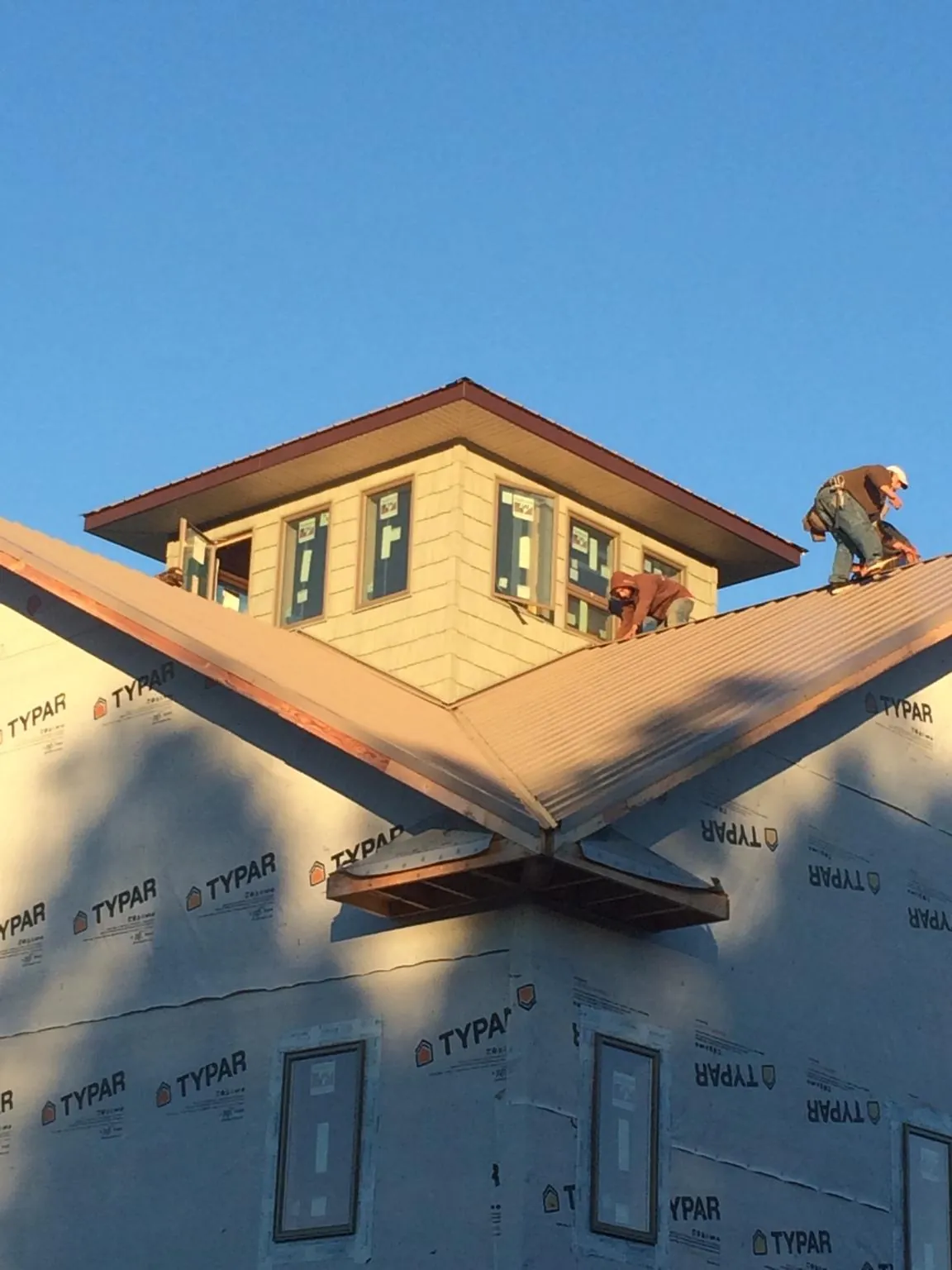 Roofers working around a rooftop cupola on a new metal roof at sunset — Roof Waterproofing in Annville by Roofing Brothers
